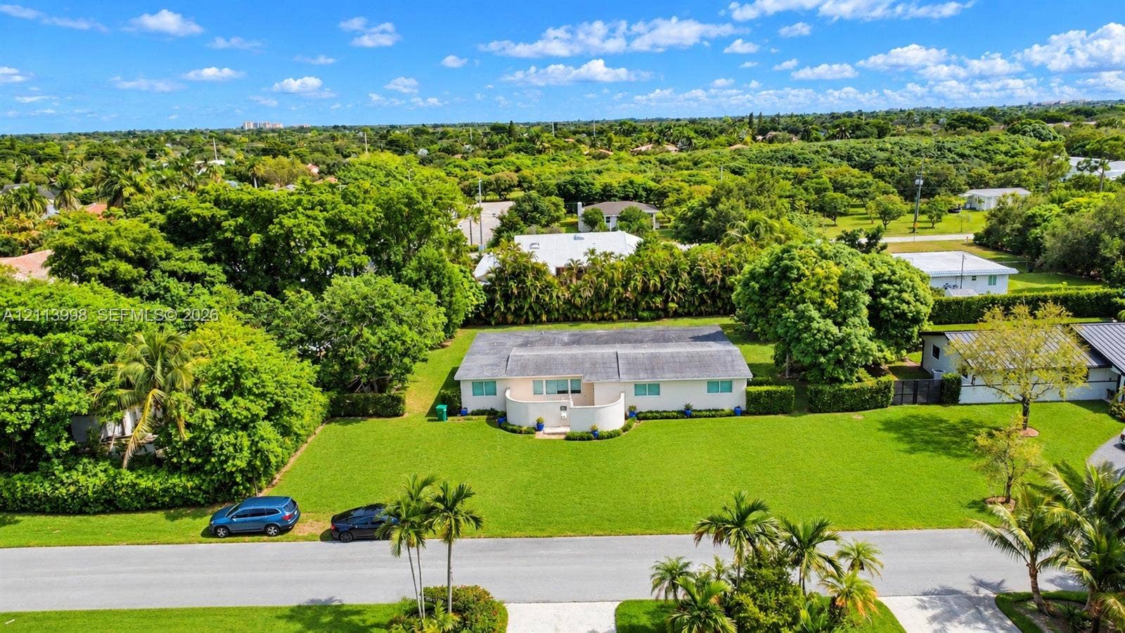 16455 SW 91st Avenue, Palmetto Bay, FL 33157 Single-story residence featuring a gated entry courtyard, expansive front lawn, and mature landscaping
