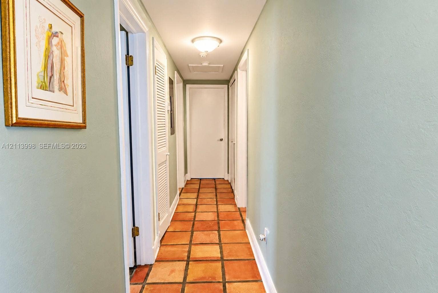 16455 SW 91st Avenue, Palmetto Bay, FL 33157 Hallway featuring terracotta tile flooring, smooth-finish walls, and white louvered closet doors