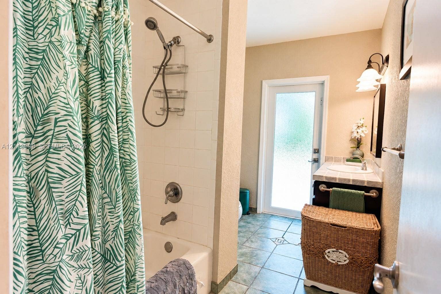 16455 SW 91st Avenue, Palmetto Bay, FL 33157 Bathroom featuring a tub-shower combination with tile surround, vanity with tile countertop, ceramic floor tiling, and a glass-paneled exterior door