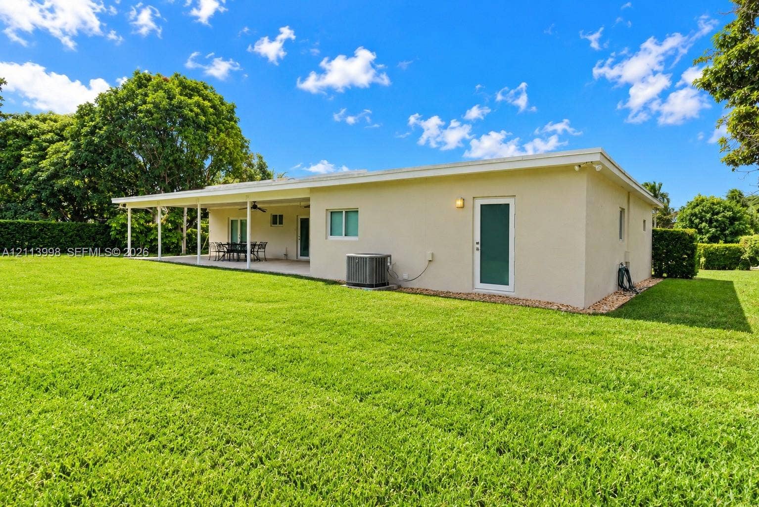 16455 SW 91st Avenue, Palmetto Bay, FL 33157 Spacious backyard featuring a manicured lawn, expansive covered patio, and mature perimeter landscaping