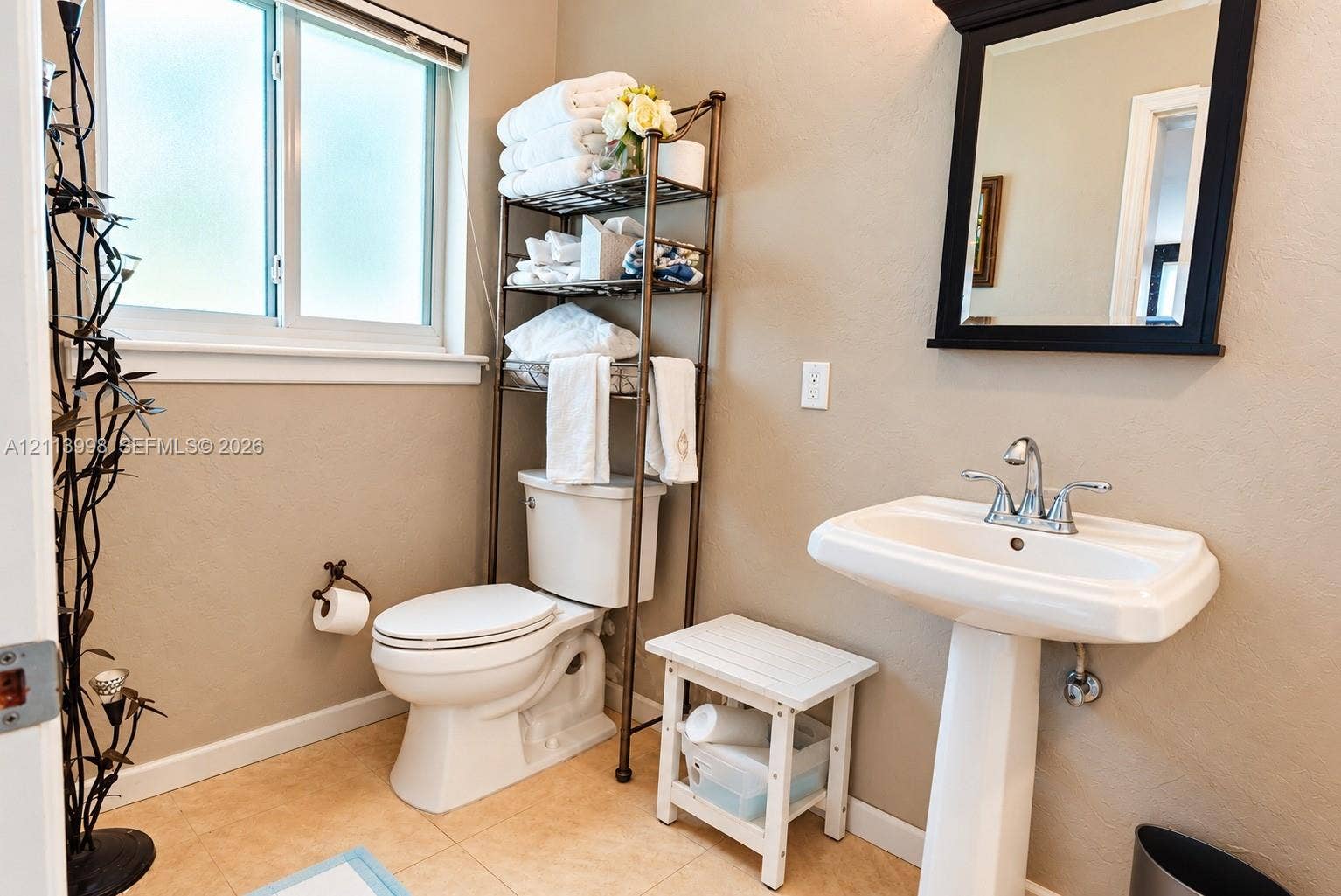 16455 SW 91st Avenue, Palmetto Bay, FL 33157 Pedestal sink with chrome dual-handle faucet, wall-mounted mirror with dark frame, privacy-glass window, and neutral tile flooring