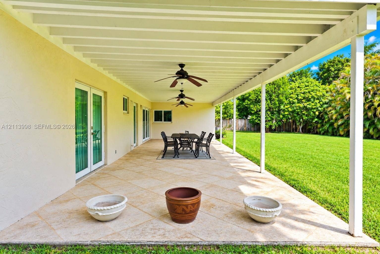 16455 SW 91st Avenue, Palmetto Bay, FL 33157 Covered outdoor patio featuring tile flooring, ceiling fans, structural support posts, and double glass doors