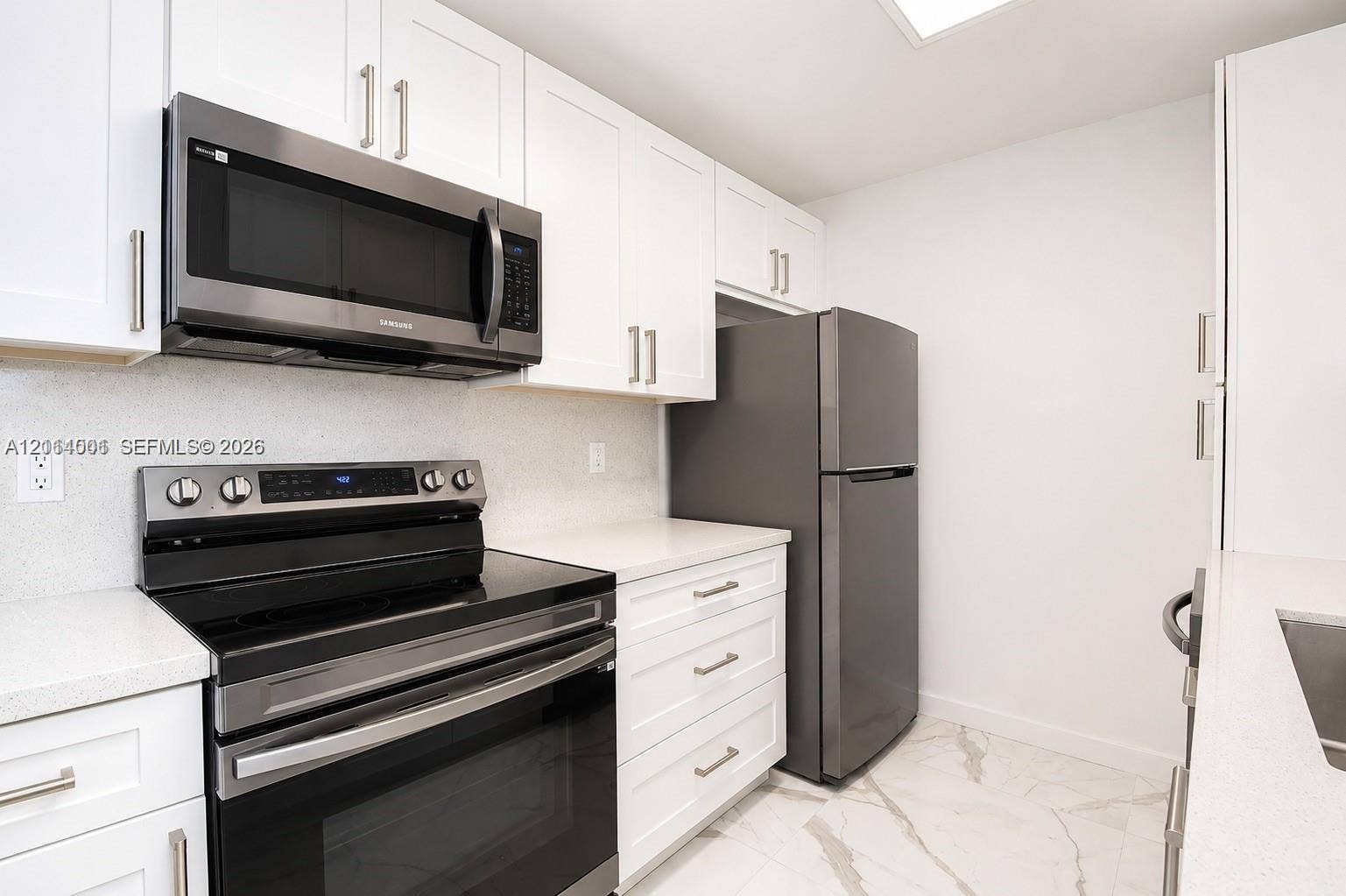 2611 SW 13th Avenue, #1-2, Fort Lauderdale, Fort Lauderdale, FL 33315 Kitchen featuring white shaker-style cabinetry, solid-surface countertops, stainless steel appliances, and large-format tile flooring with veining