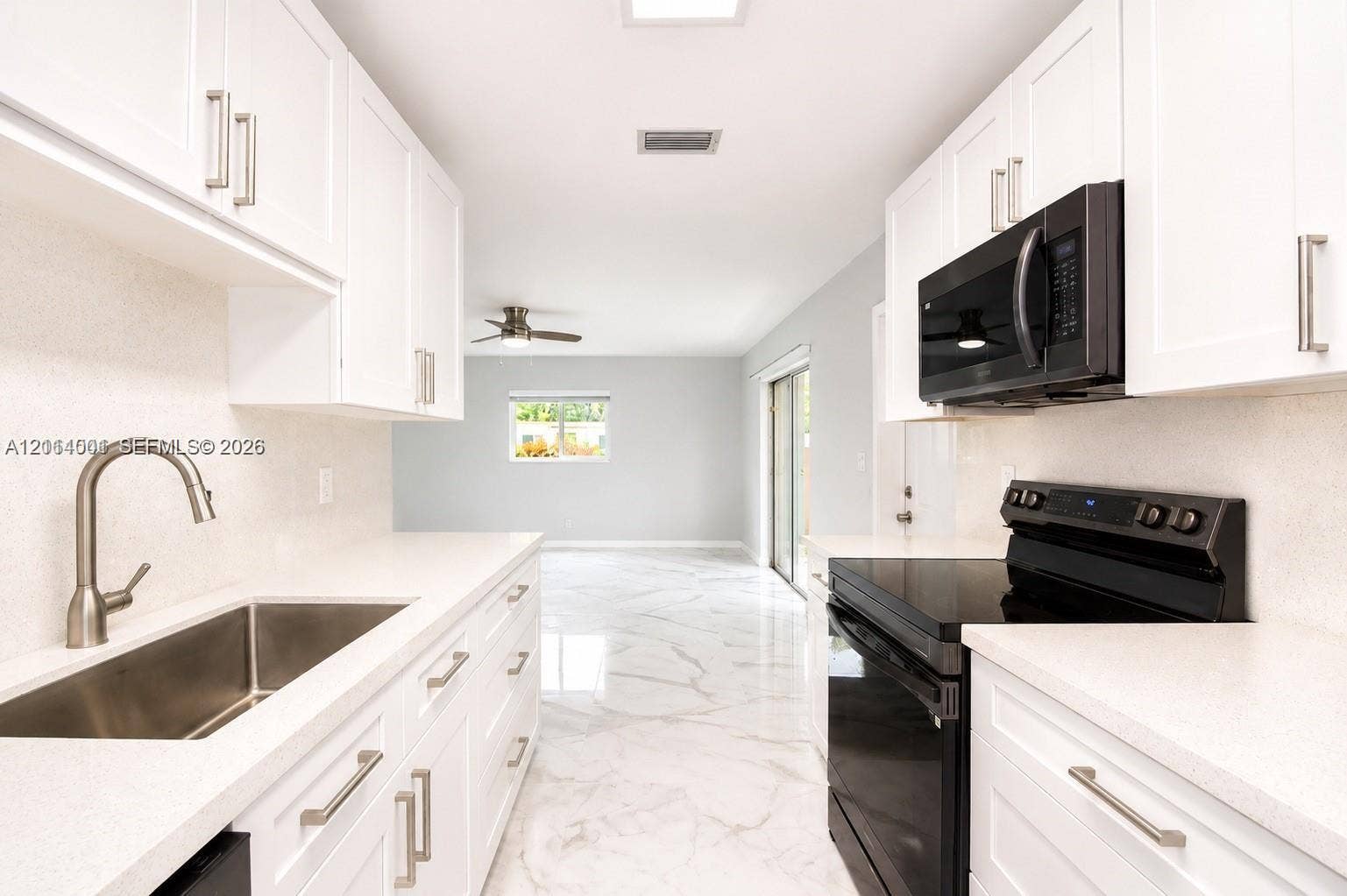 2611 SW 13th Avenue, #1-2, Fort Lauderdale, Fort Lauderdale, FL 33315 Kitchen featuring white Shaker-style cabinetry, solid-surface countertops, an undermount stainless steel sink with a high-arch faucet, black appliance suite, and polished stone-finish flooring