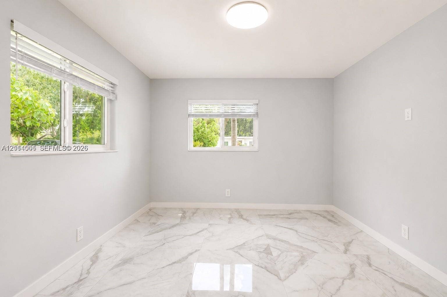 2611 SW 13th Avenue, #1-2, Fort Lauderdale, Fort Lauderdale, FL 33315 Neutral-toned interior room featuring large-format stone-finish tile flooring, two horizontal sliding windows, and a central flush-mount ceiling light fixture