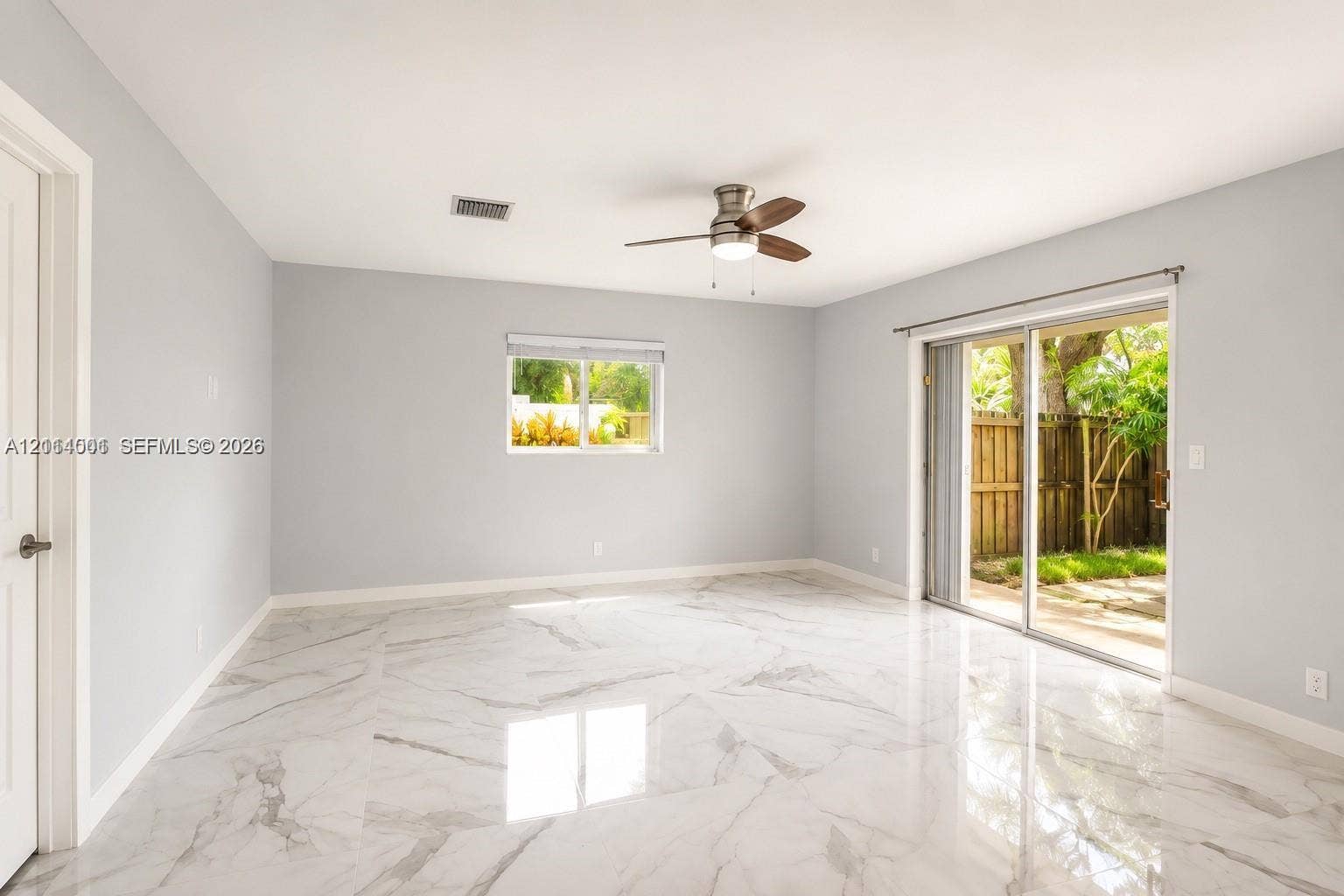 2611 SW 13th Avenue, #1-2, Fort Lauderdale, Fort Lauderdale, FL 33315 Interior space featuring light-toned flooring with natural veining patterns, sliding glass doors, and a ceiling fan with integrated lighting