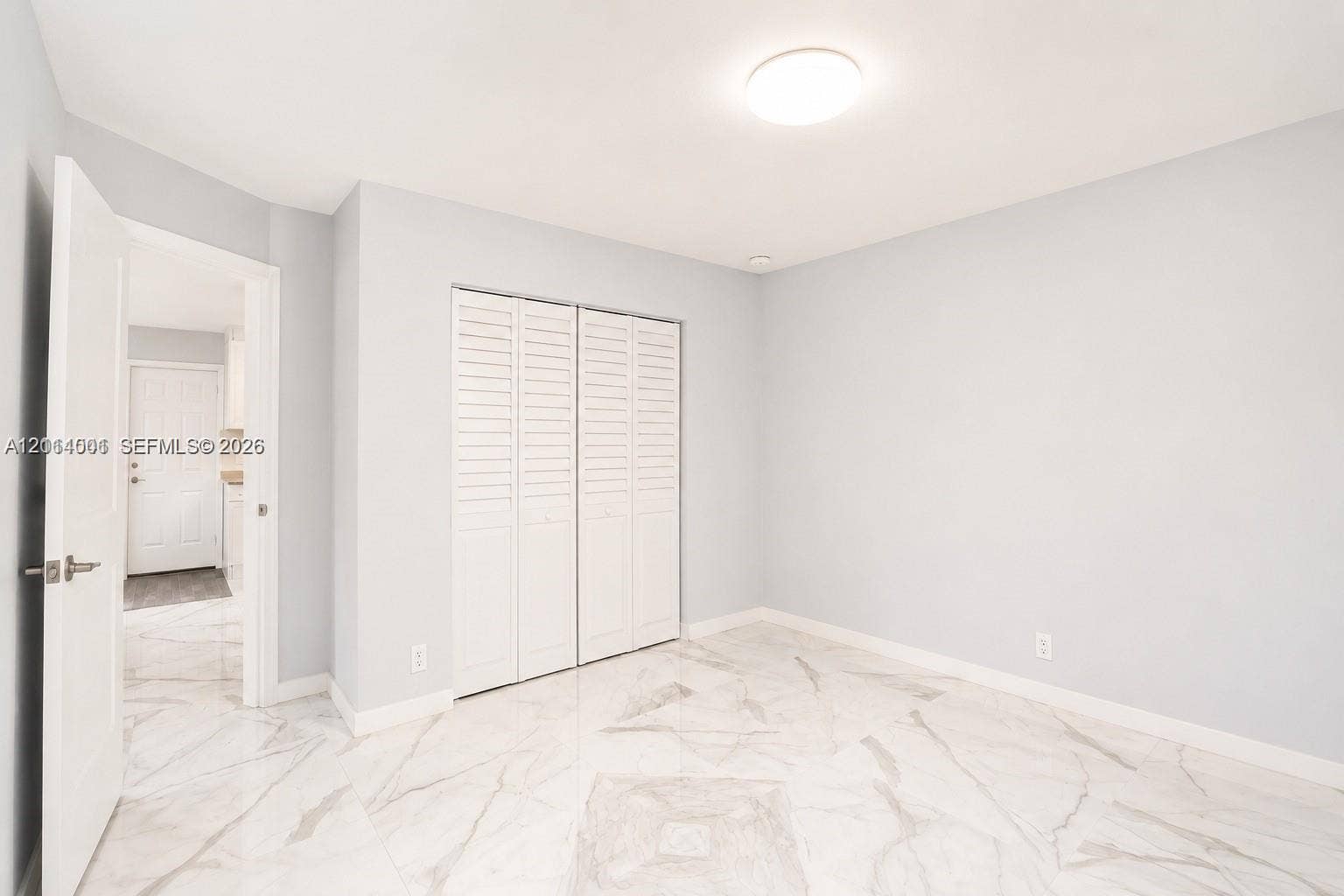 2611 SW 13th Avenue, #1-2, Fort Lauderdale, Fort Lauderdale, FL 33315 Interior space featuring polished stone-finish flooring, white louvered-style closet doors, and a flush-mount ceiling light fixture