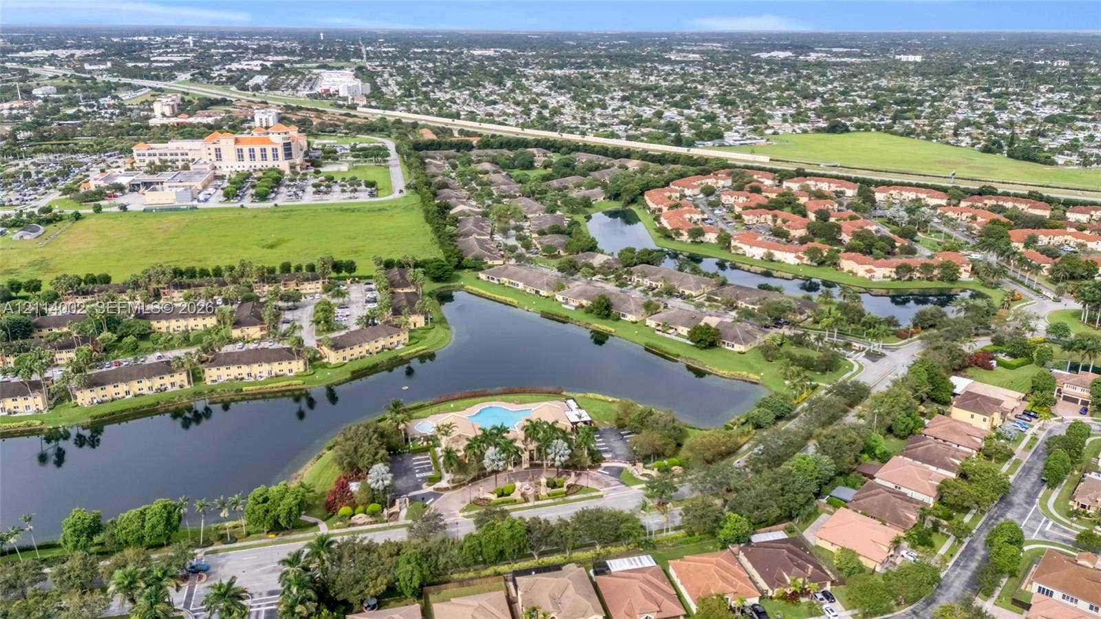 1495 NE 33rd Avenue, #107, Homestead, Homestead, FL 33033 Aerial perspective of community featuring a centralized swimming pool, extensive water frontage, and manicured landscaping