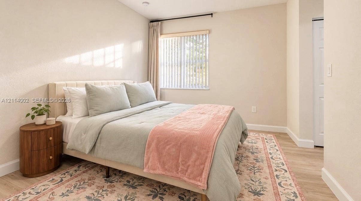 1495 NE 33rd Avenue, #107, Homestead, Homestead, FL 33033 Neutral-toned room featuring light wood-finish flooring, a vaulted ceiling, and a window with vertical blinds