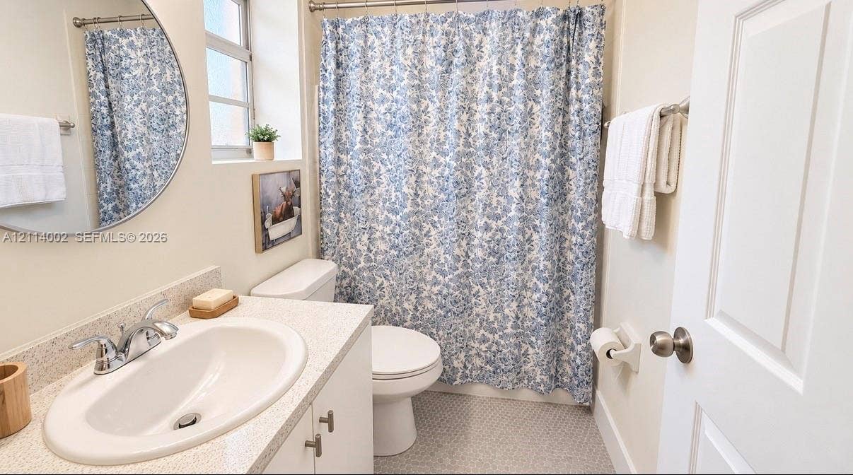 1495 NE 33rd Avenue, #107, Homestead, Homestead, FL 33033 Bathroom featuring a vanity with a neutral solid-surface countertop, an integrated oval basin, a round wall-mounted mirror, and tile flooring
