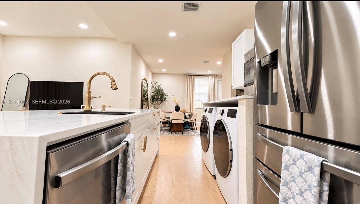 1495 NE 33rd Avenue, #107, Homestead, Homestead, FL 33033 Kitchen featuring a stone-surface island, stainless steel appliances, recessed lighting, and wood-finish flooring, with an integrated laundry area