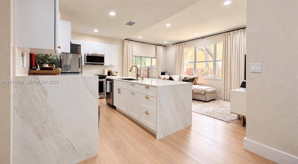 1495 NE 33rd Avenue, #107, Homestead, Homestead, FL 33033 Kitchen featuring a waterfall-edge stone countertop, shaker-style cabinetry, stainless steel appliances, and wood-finish flooring