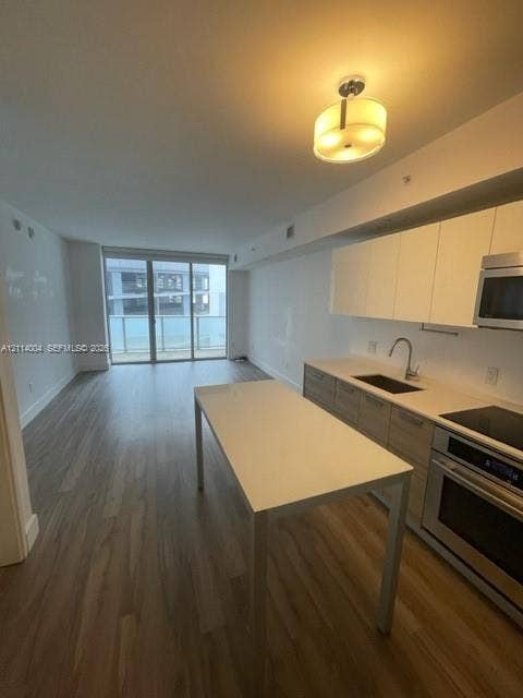 1300 Brickell Bay Drive, #1000, Miami, Miami, FL 33131 Kitchen featuring flat-panel cabinetry, light-toned countertops, built-in stainless steel appliances, wood-finish flooring, and a sliding glass door to a balcony