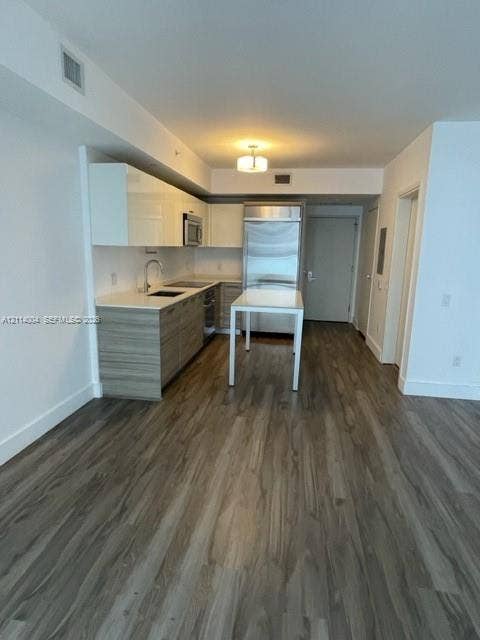 1300 Brickell Bay Drive, #1000, Miami, Miami, FL 33131 Kitchen featuring high-gloss white upper cabinetry, wood-finish lower cabinetry, stone countertops, stainless steel appliances, and wood-finish flooring