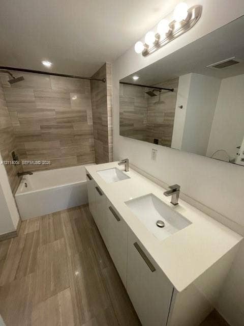 1300 Brickell Bay Drive, #1000, Miami, Miami, FL 33131 Dual-sink vanity with white cabinetry, solid surface countertop, and brushed metal hardware, complemented by horizontal tile flooring and matching wall tile in the tub surround