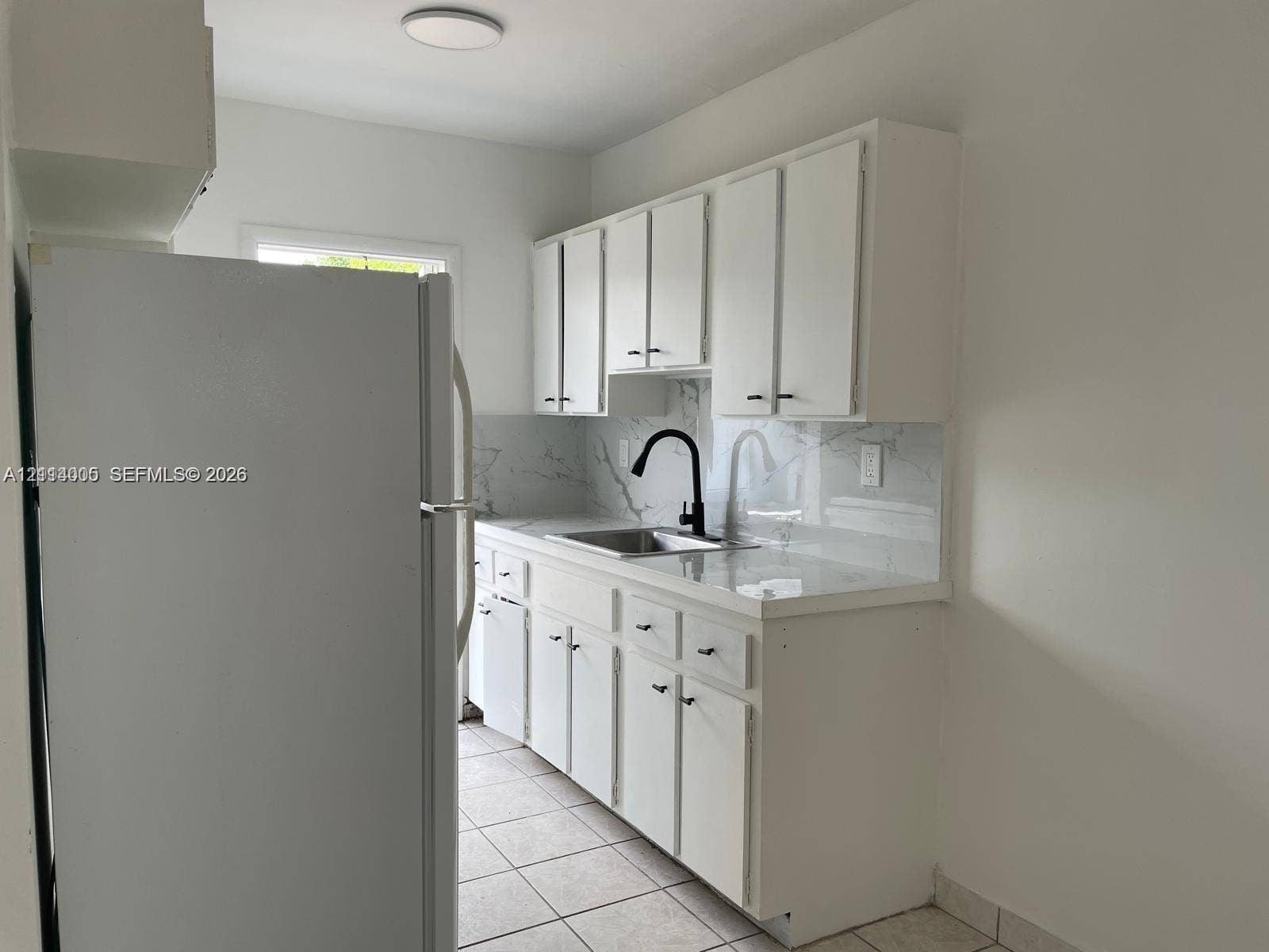 6025 Polk Street, #7, Hollywood, Hollywood, FL 33024 Kitchen featuring white cabinetry, stone-surface countertops, full-height stone backsplash, matte black faucet, and ceramic tile flooring