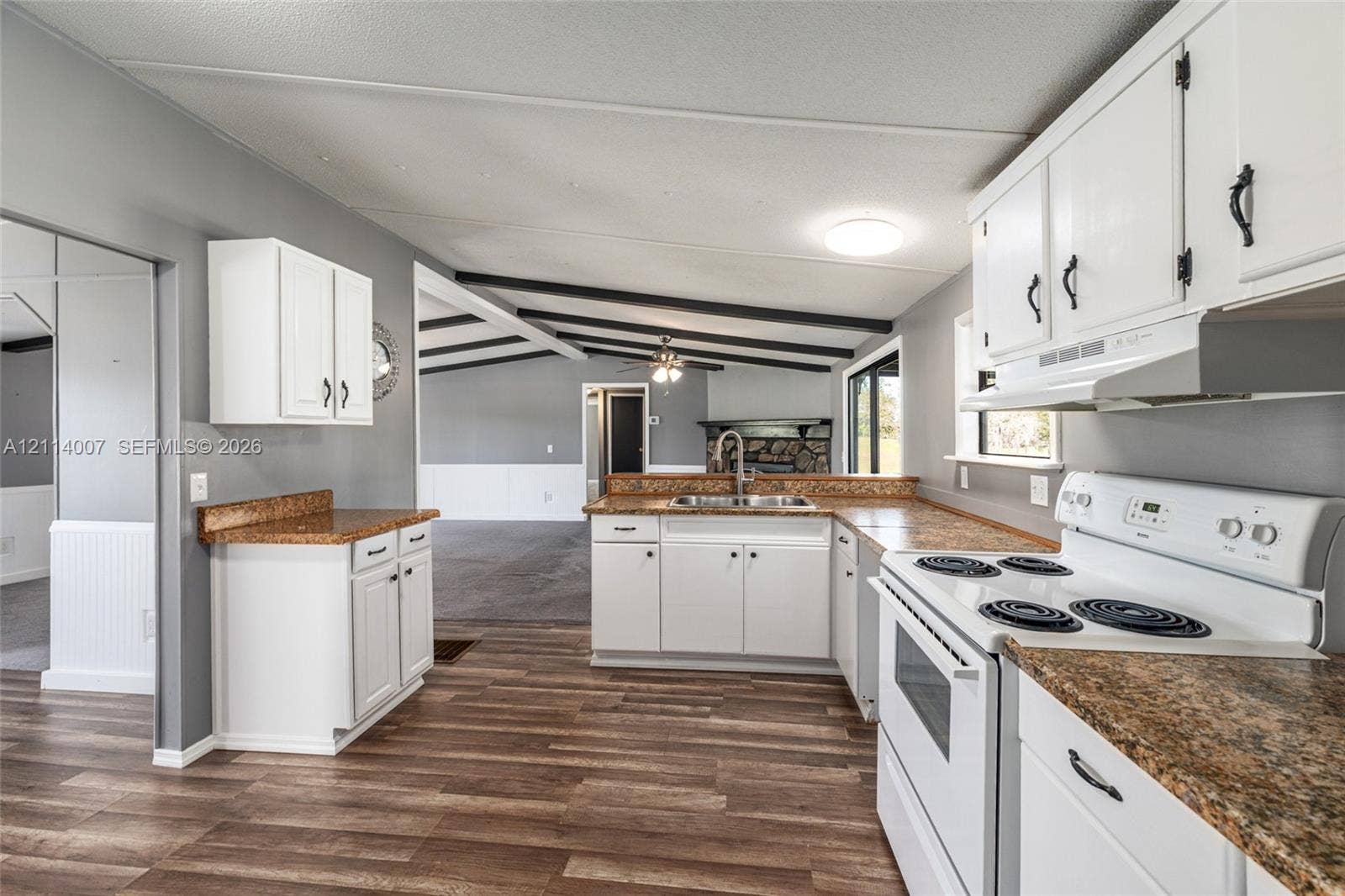 5600 SE 39th Street, Trenton, FL 32693 Kitchen featuring white cabinetry, stone-finish countertops, wood-finish flooring, and a stainless steel sink with a high-arch faucet
