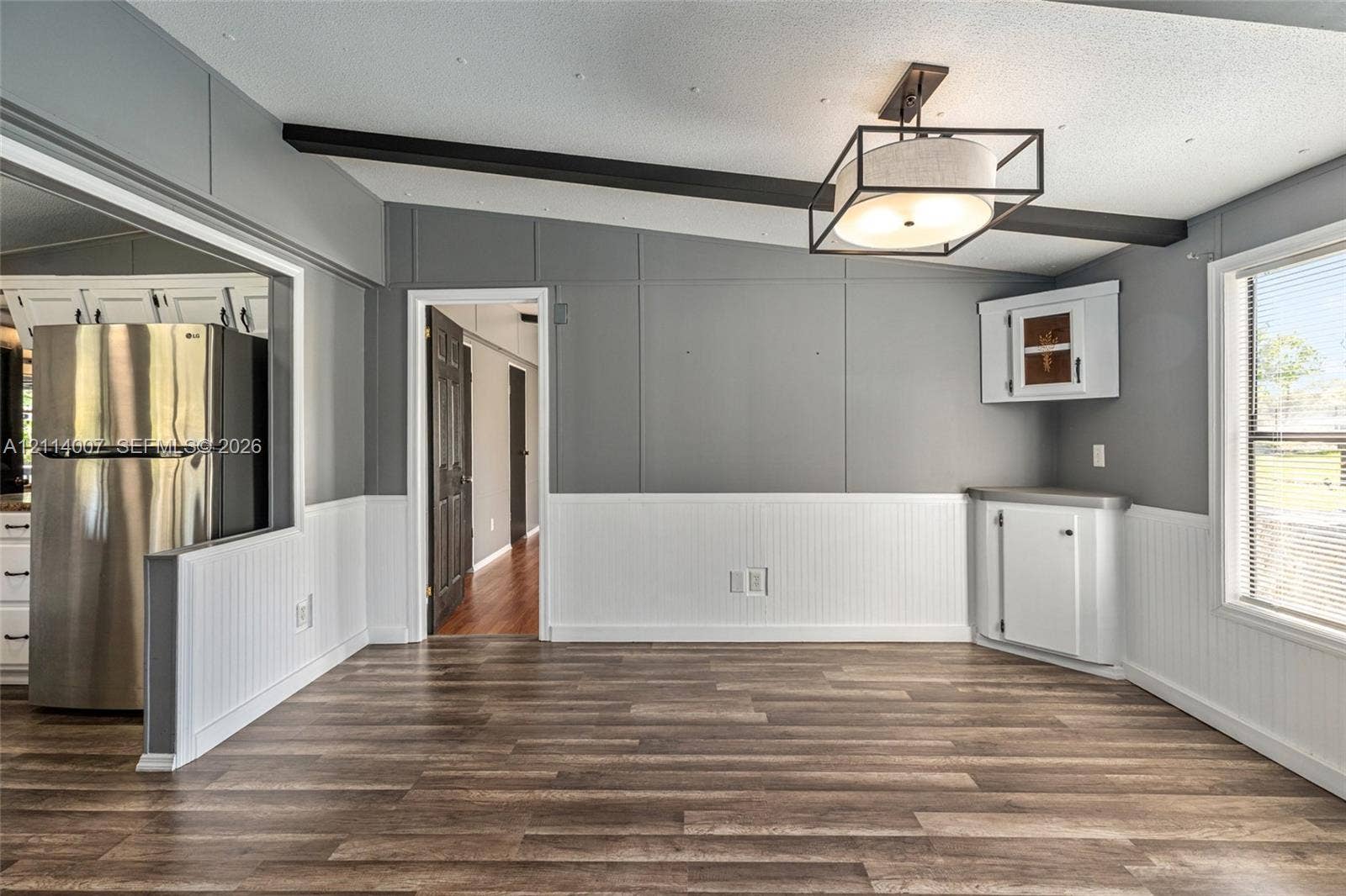 5600 SE 39th Street, Trenton, FL 32693 Interior space featuring wood-finish flooring, beadboard wainscoting, exposed ceiling beam, geometric metal-frame light fixture, and built-in corner cabinetry