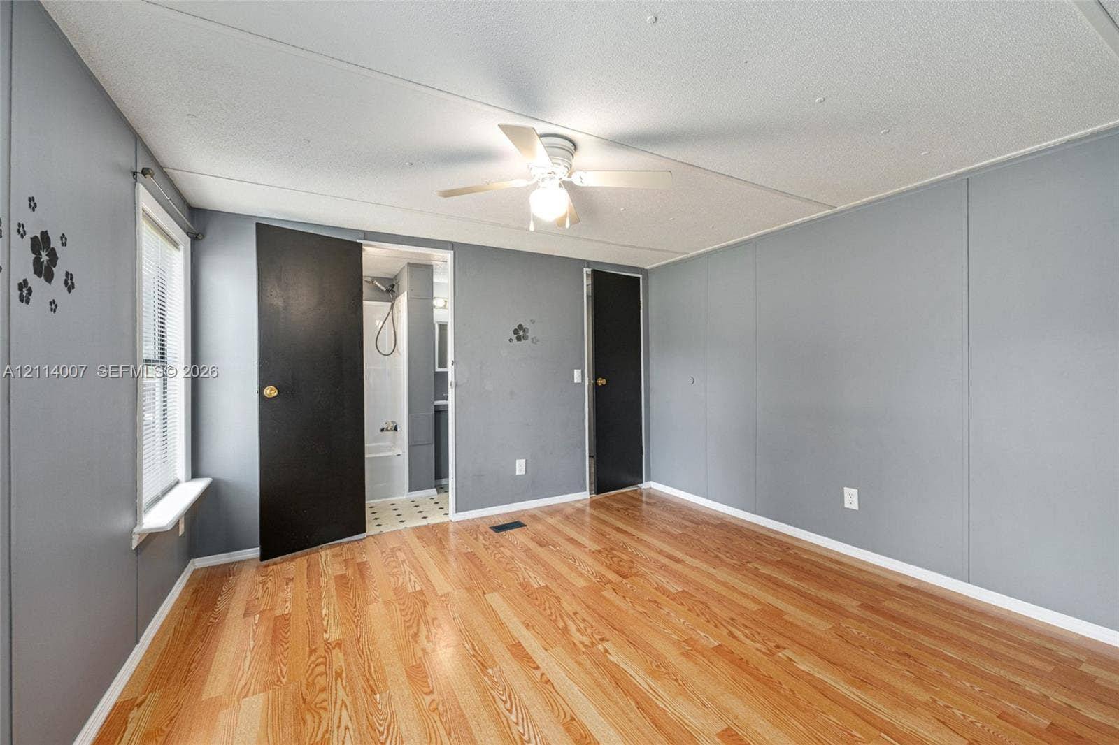 5600 SE 39th Street, Trenton, FL 32693 Room featuring wood-finish flooring, a ceiling fan with integrated lighting, window with sill, and two solid-core doors