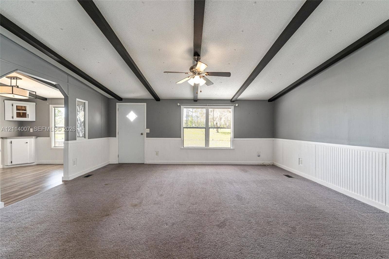 5600 SE 39th Street, Trenton, FL 32693 Room featuring high-contrast decorative ceiling beams, beadboard wainscoting, and a central ceiling fan