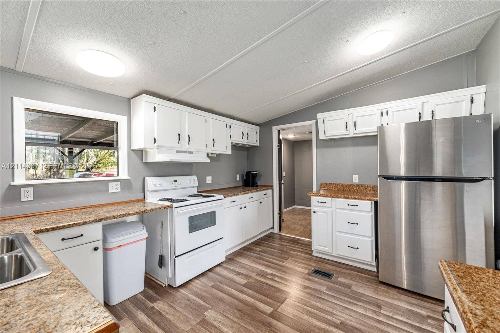 5600 SE 39th Street, Trenton, FL 32693 Kitchen featuring white cabinetry, stone-finish countertops, stainless steel refrigerator, white freestanding range, and wood-finish flooring