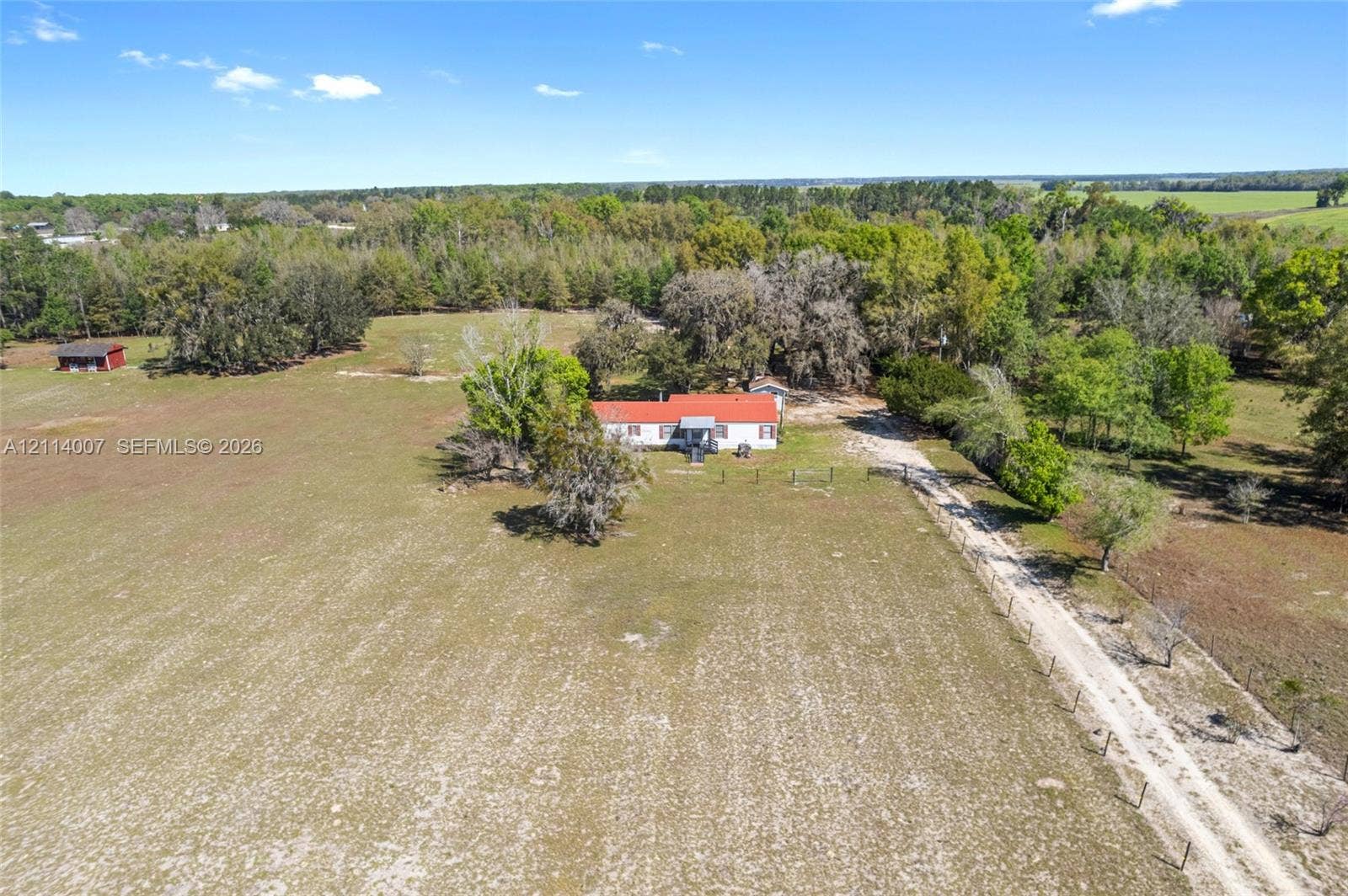 5600 SE 39th Street, Trenton, FL 32693 Single-story residence featuring a metal roof, expansive acreage, mature trees, and a private gravel drive