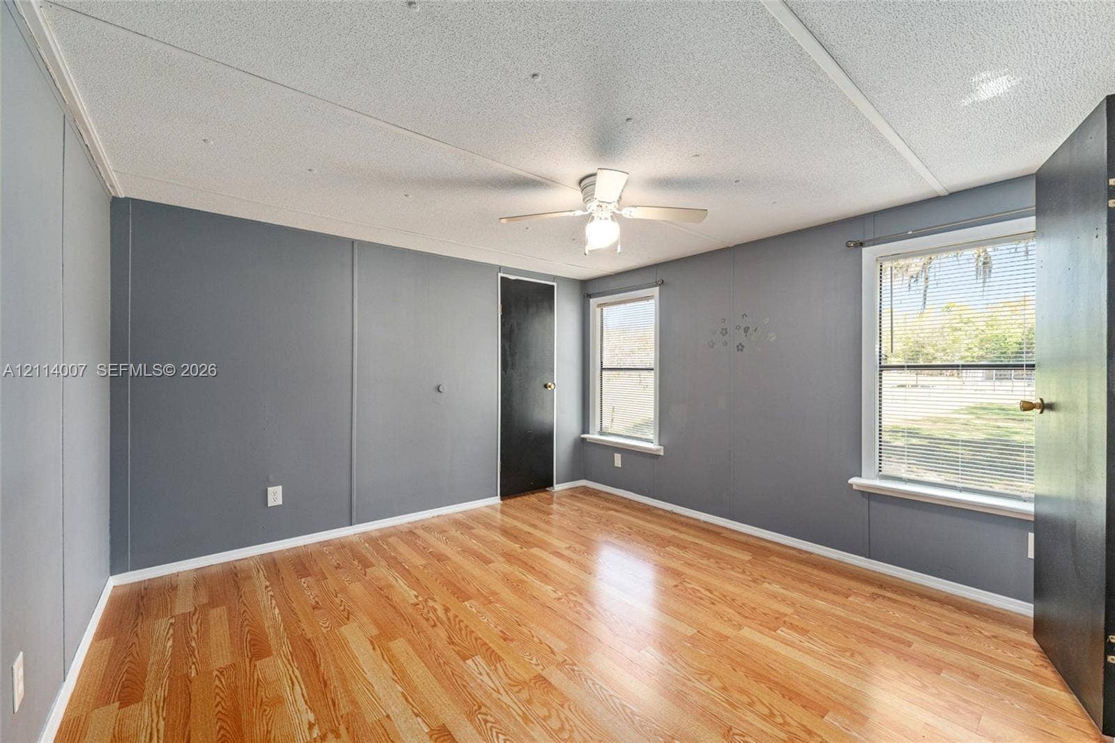 5600 SE 39th Street, Trenton, FL 32693 Room featuring wood-finish flooring, dual windows, matte black interior doors, and a ceiling fan with light fixture