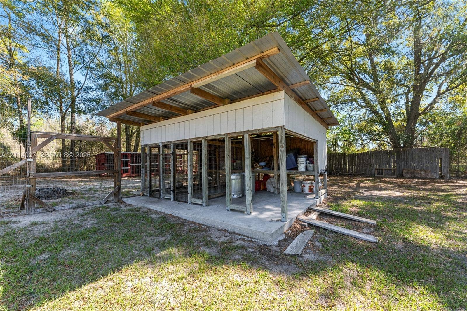 5600 SE 39th Street, Trenton, FL 32693 Outdoor structure featuring a concrete foundation, shed-style metal roofing, vertical siding, and an open-frame design with wire mesh panels