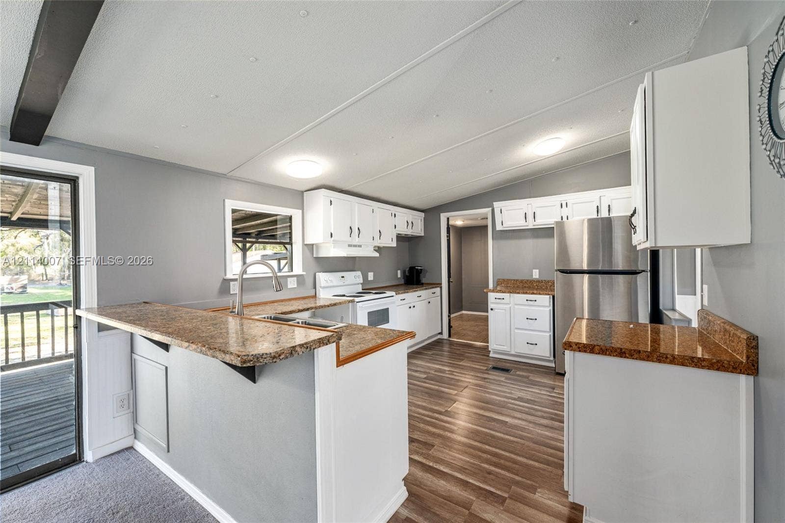 5600 SE 39th Street, Trenton, FL 32693 Kitchen featuring white shaker-style cabinetry, stone-finish countertops, stainless steel appliances, and wood-finish flooring