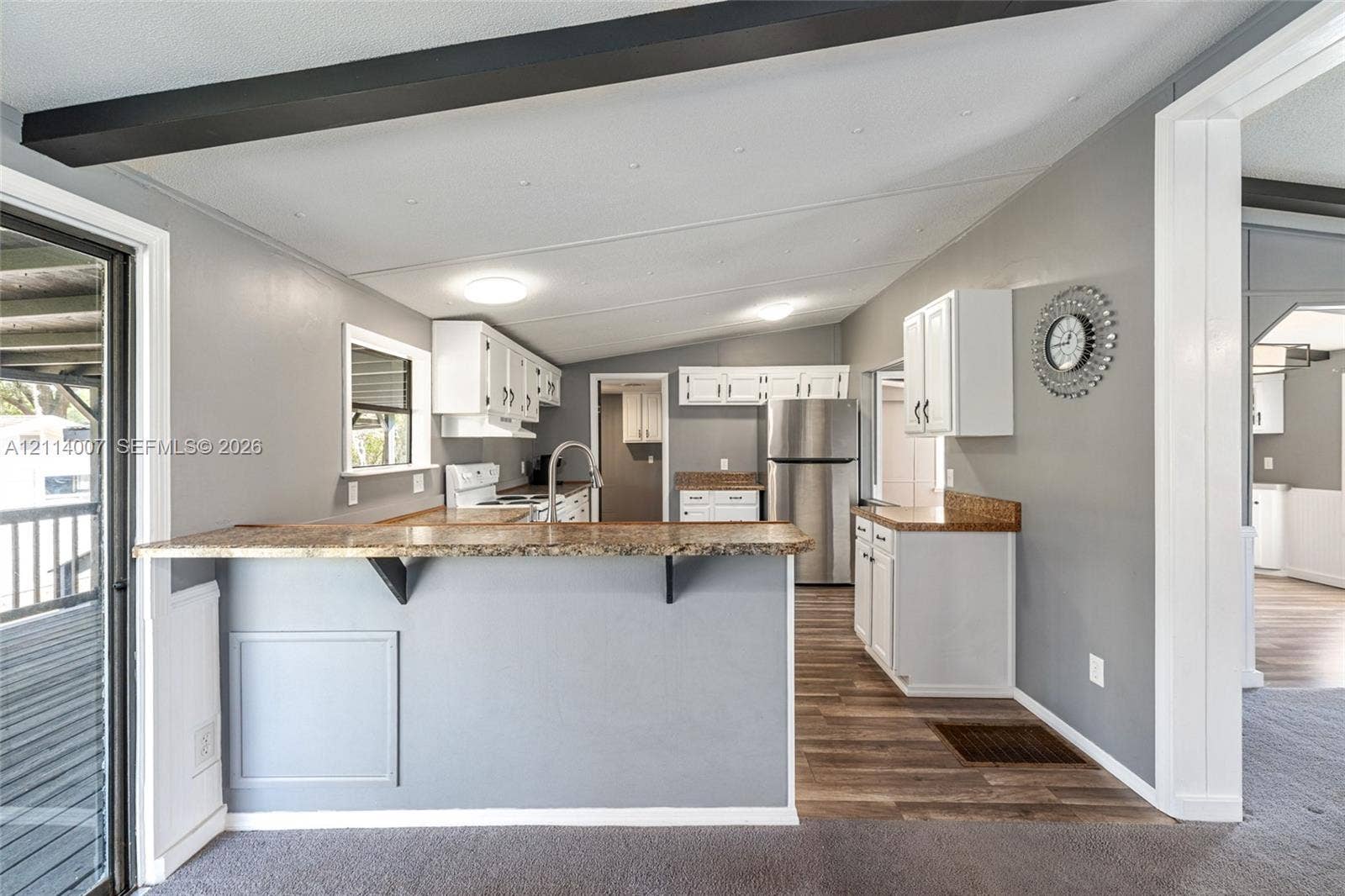 5600 SE 39th Street, Trenton, FL 32693 Kitchen featuring white cabinetry, stone-finish countertops, stainless steel appliances, a breakfast bar, and wood-finish flooring