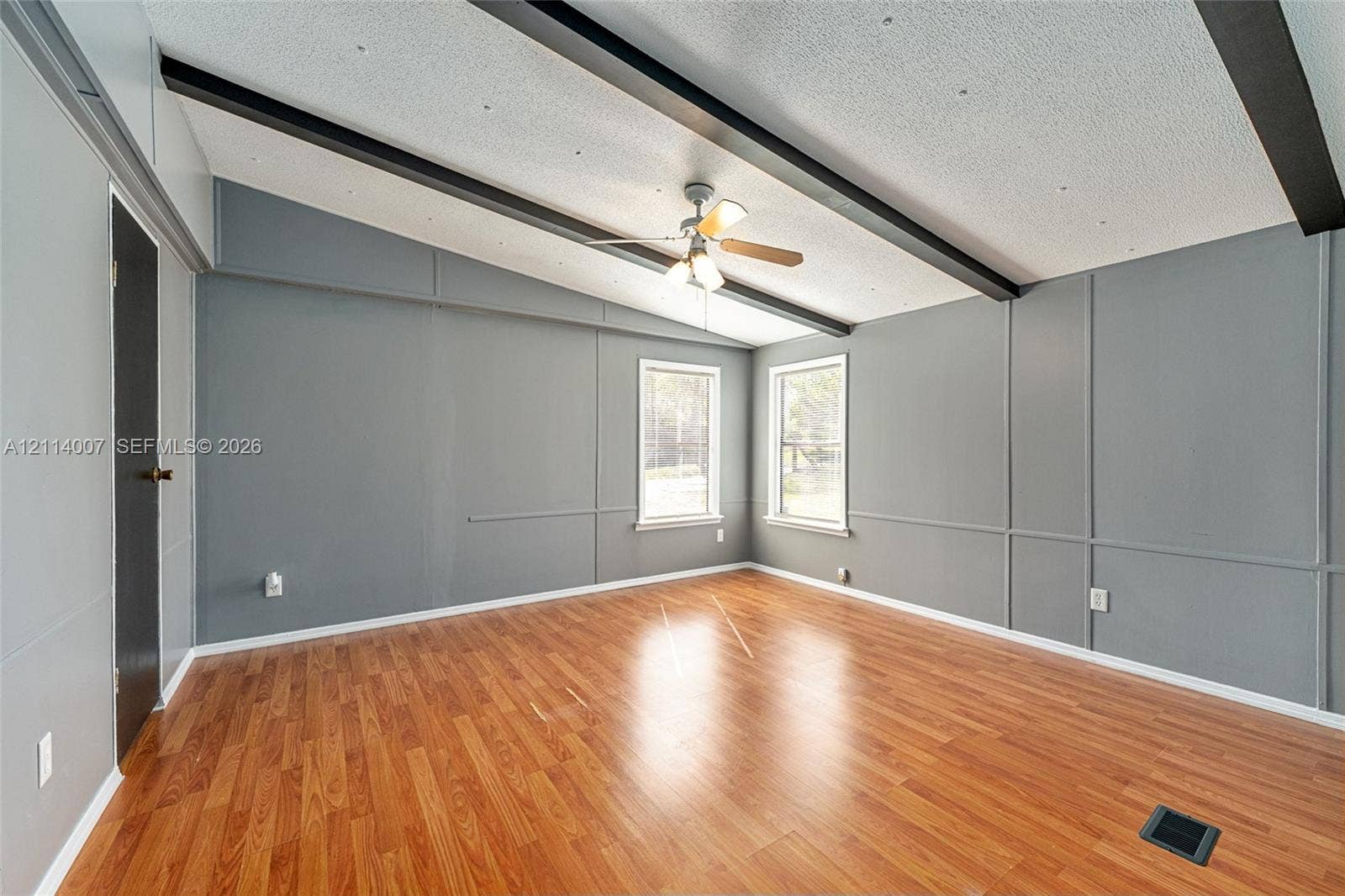 5600 SE 39th Street, Trenton, FL 32693 Vaulted ceiling featuring exposed dark beams, wood-finish flooring, wainscoting-style wall paneling, and a central ceiling fan with integrated lighting