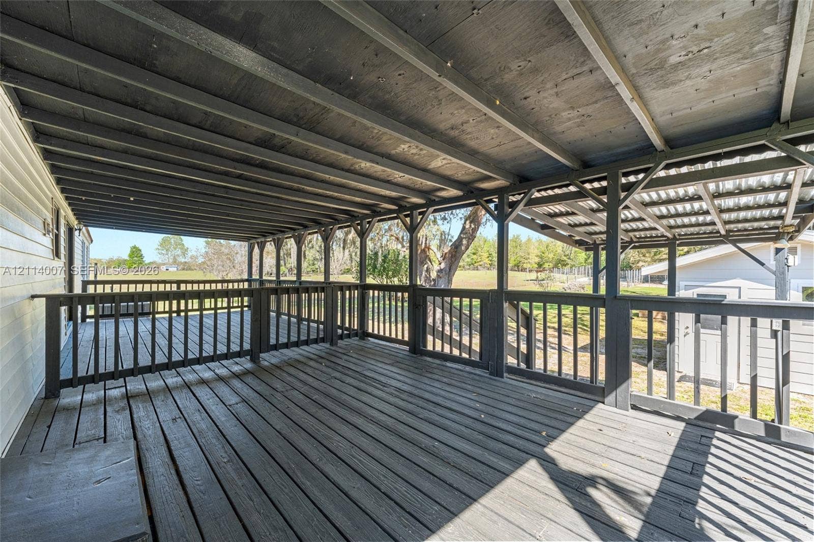5600 SE 39th Street, Trenton, FL 32693 Covered outdoor deck featuring wood decking, a dark-toned timber frame structure, and black painted wooden balustrades