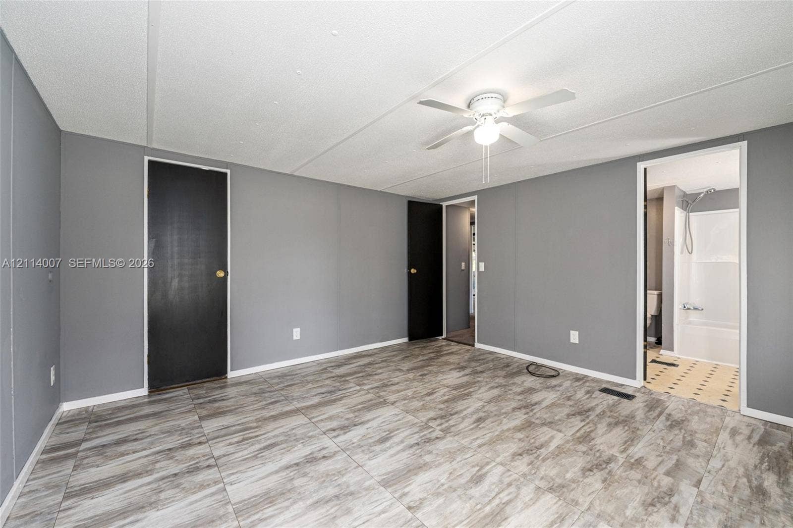 5600 SE 39th Street, Trenton, FL 32693 Interior room featuring wood-finish flooring, two solid-core doors, and a ceiling-mounted light fixture with integrated fan