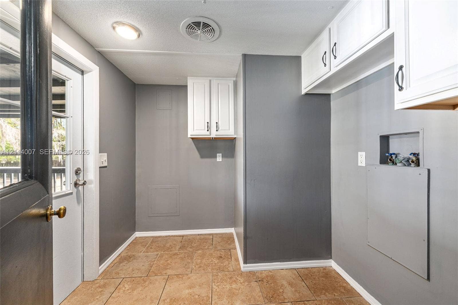 5600 SE 39th Street, Trenton, FL 32693 Utility room featuring tile flooring, white upper cabinetry, dedicated plumbing hookups, and a glass-paneled exterior door
