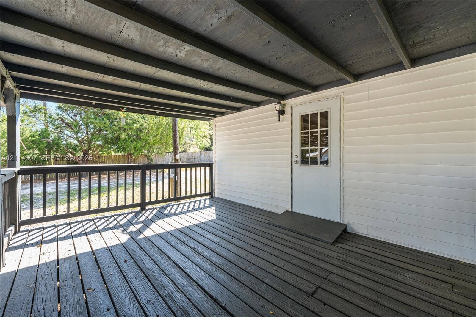 5600 SE 39th Street, Trenton, FL 32693 Covered porch featuring dark wood-finish decking, horizontal vinyl siding, a multi-pane glass door, and a perimeter railing