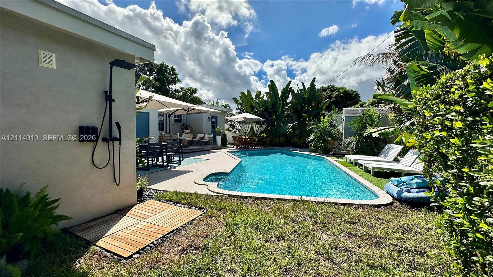 1161-1163 SW 30th Street, Fort Lauderdale, FL 33315 Outdoor space featuring a swimming pool, wood-slat shower base, wall-mounted matte black exterior shower fixture, and landscaped perimeter foliage
