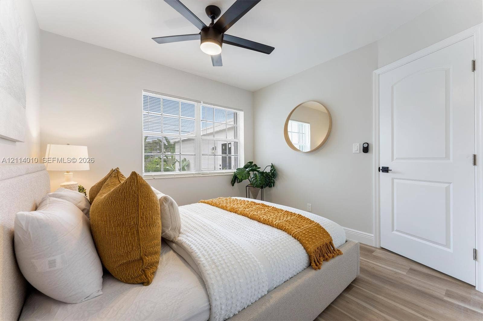 1161-1163 SW 30th Street, Fort Lauderdale, FL 33315 Neutral wall tones paired with wood-finish flooring, multi-pane window, matte black ceiling fan with integrated lighting, and white interior door featuring matte black hardware