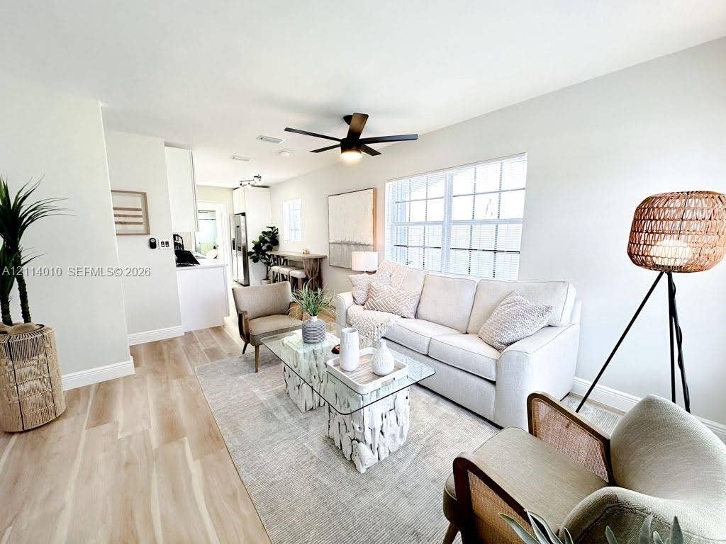 1161-1163 SW 30th Street, Fort Lauderdale, FL 33315 Living area featuring wood-finish flooring, a matte black multi-blade ceiling fan, and large grid-pane windows