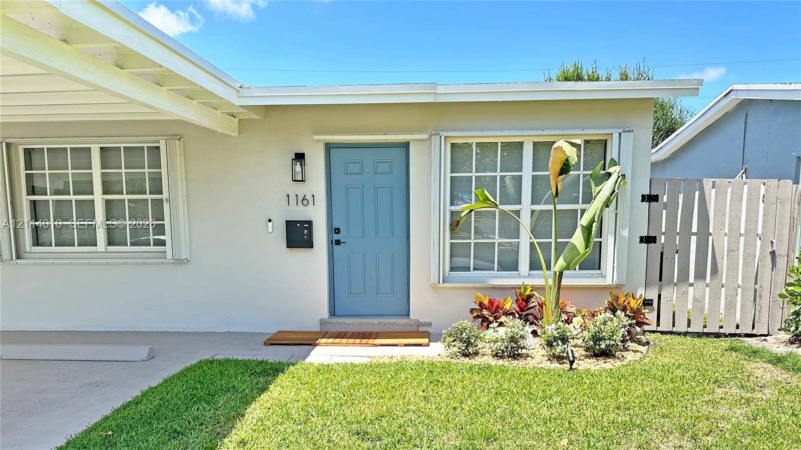 1161-1163 SW 30th Street, Fort Lauderdale, FL 33315 Exterior facade featuring a covered carport, multi-pane windows, a paneled front entry door, and a privacy fence