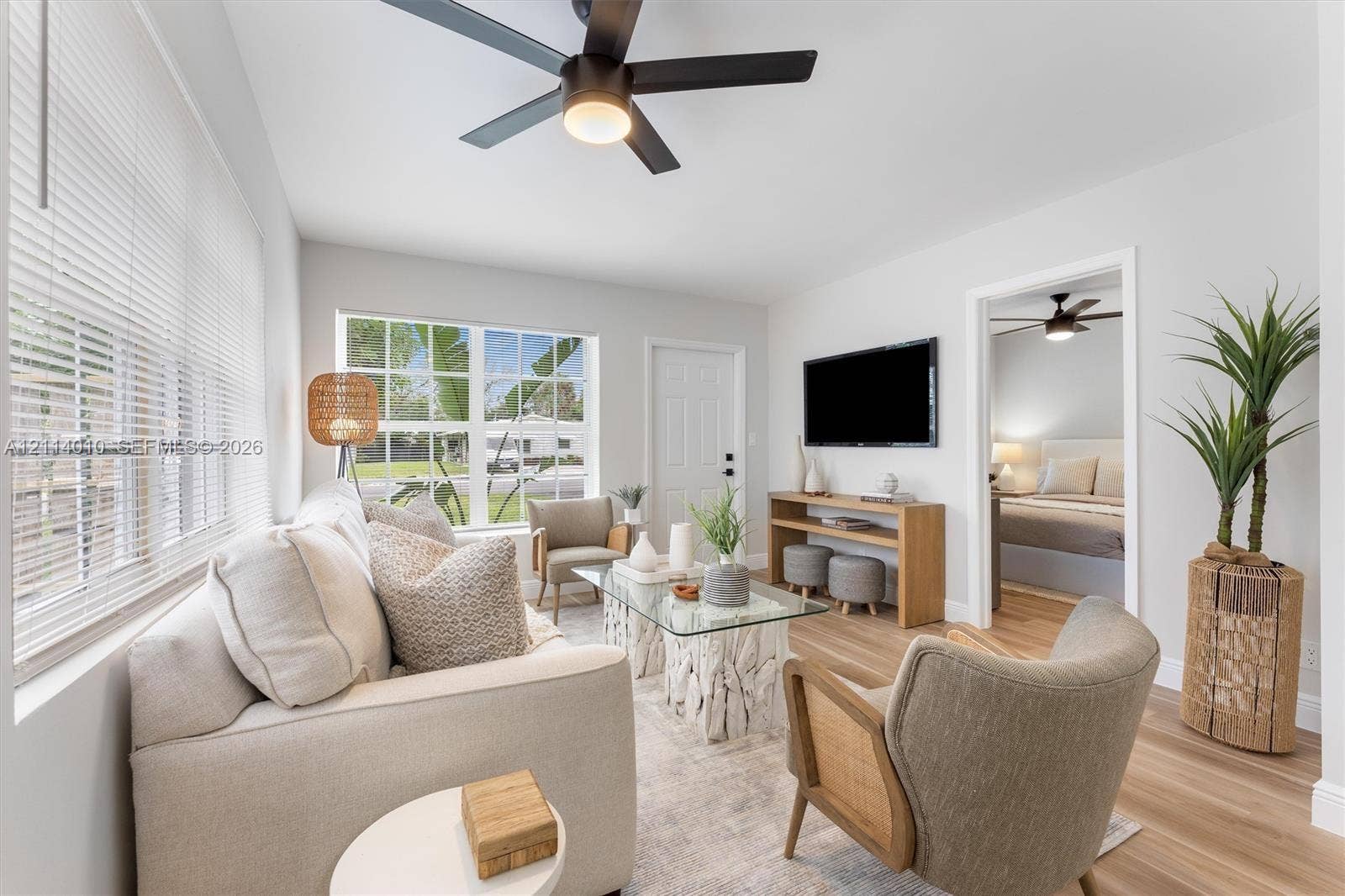 1161-1163 SW 30th Street, Fort Lauderdale, FL 33315 Living area featuring wood-finish flooring, a contemporary ceiling fan with integrated lighting, and multi-pane windows with horizontal blinds