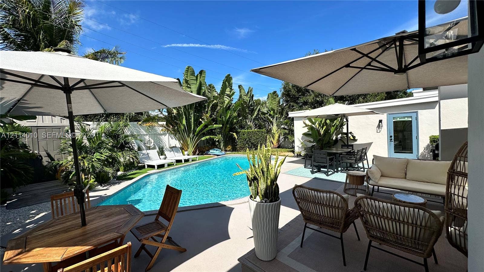 1161-1163 SW 30th Street, Fort Lauderdale, FL 33315 Outdoor space featuring a swimming pool, concrete patio, white vinyl perimeter fencing, and mature tropical landscaping