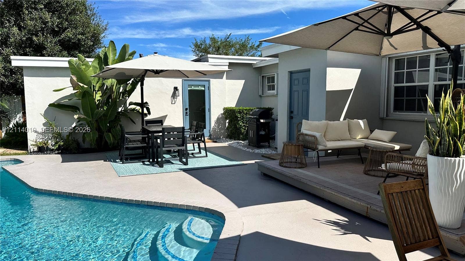 1161-1163 SW 30th Street, Fort Lauderdale, FL 33315 Private courtyard featuring a swimming pool with integrated steps, concrete patio surfacing, raised wood-finish deck, and light-colored exterior walls with blue-trimmed doors