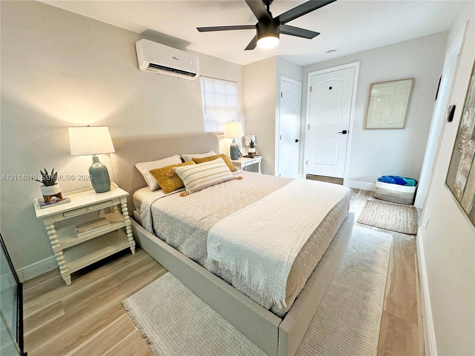 1161-1163 SW 30th Street, Fort Lauderdale, FL 33315 Room featuring wood-finish flooring, a wall-mounted ductless air conditioning unit, a matte black ceiling fan with an integrated light, and a white interior door with a matte black lever handle