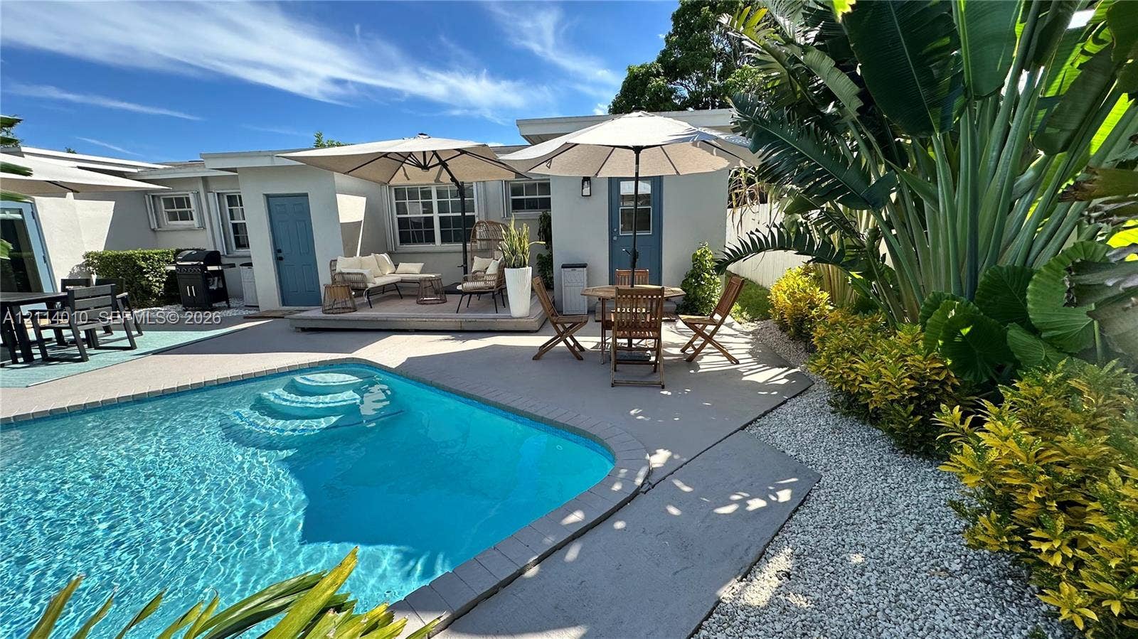 1161-1163 SW 30th Street, Fort Lauderdale, FL 33315 Outdoor space featuring an in-ground swimming pool, concrete patio, gravel landscaping, and mature tropical greenery