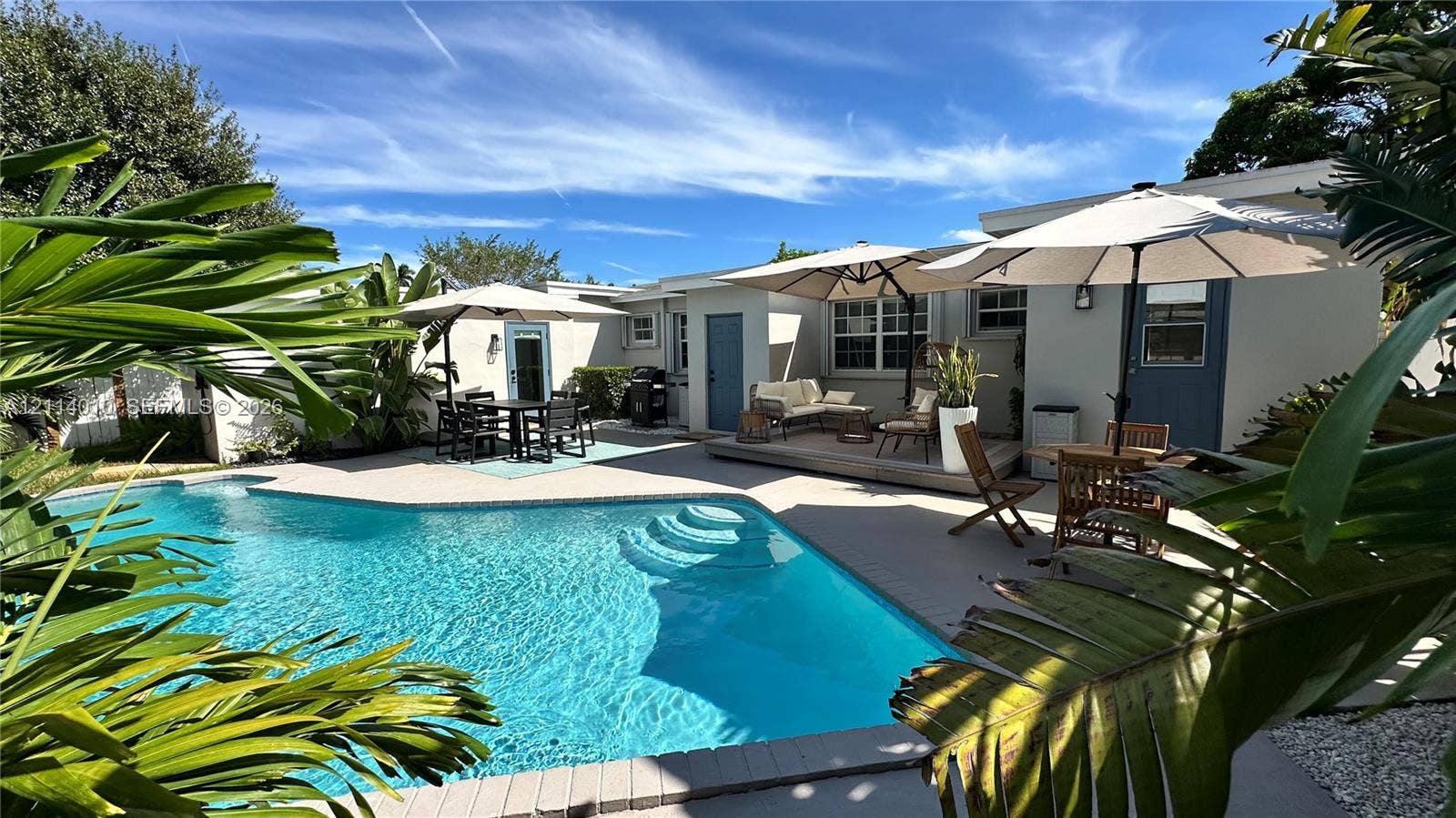 1161-1163 SW 30th Street, Fort Lauderdale, FL 33315 Swimming pool with integrated steps, expansive paved patio, raised wooden deck, and mature tropical landscaping