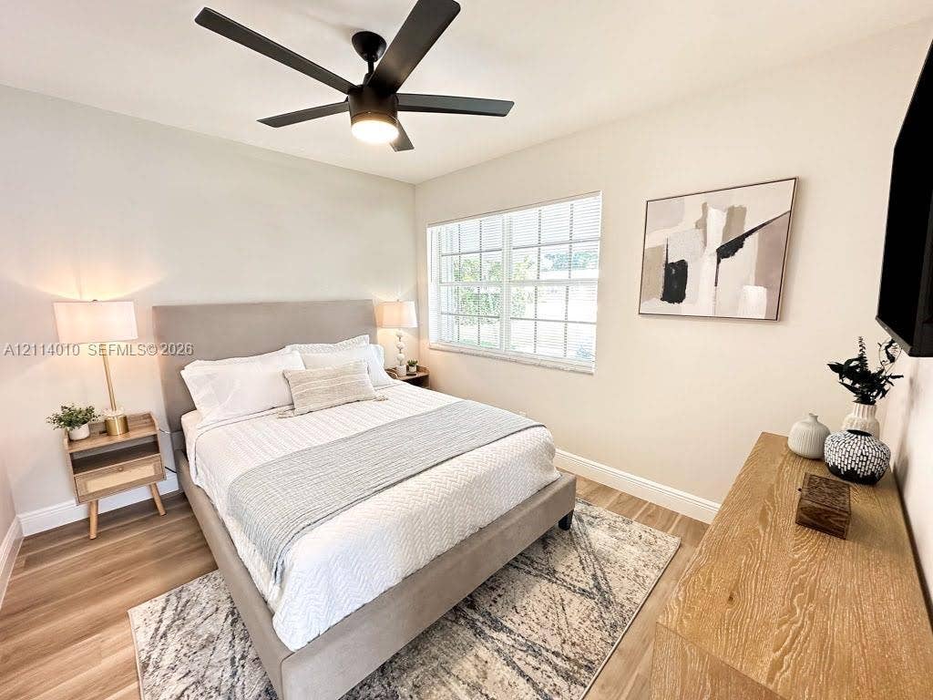 1161-1163 SW 30th Street, Fort Lauderdale, FL 33315 Neutral interior featuring wood-finish flooring, a multi-pane window, and a matte black ceiling fan with an integrated light fixture