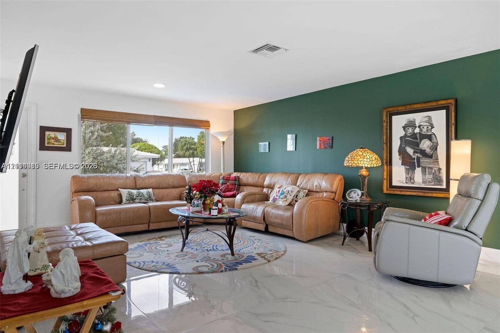 Large-format light-toned tile flooring, deep green accent wall, and expansive window with natural lighting