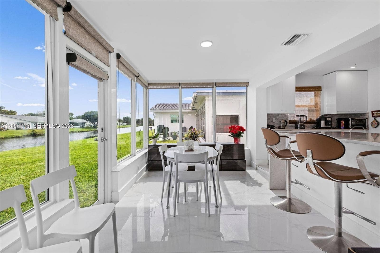 Sunroom featuring floor-to-ceiling windows, large-format tile flooring, recessed lighting, and a breakfast bar with stone-finish countertops