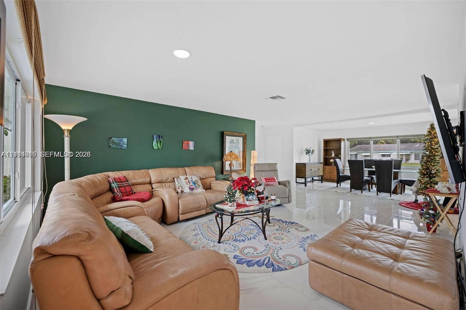 Open living area featuring polished tile flooring, recessed lighting, and a prominent green accent wall