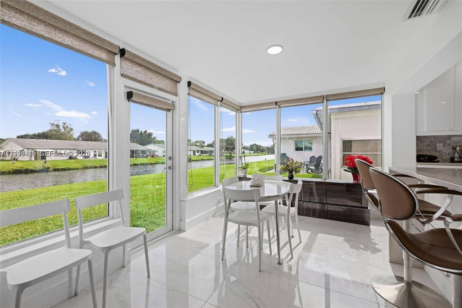 Sunroom featuring floor-to-ceiling windows, polished tile flooring, and direct access to a waterfront exterior
